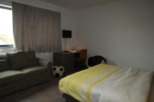 a bedroom with a bed and a couch and a desk at Résidence la floraison in Brussels
