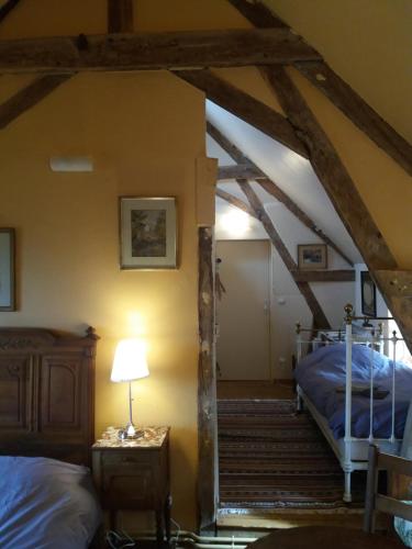 an attic room with two beds and a lamp at La Berlandière in Le Merlerault
