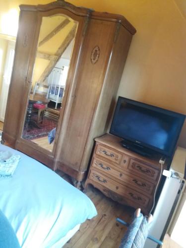 a bedroom with a dresser with a tv and a mirror at La Berlandière in Le Merlerault