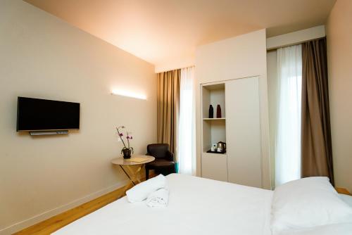 a hotel room with two beds and a tv on the wall at Hotel Politeama in Palermo