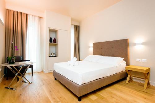 a bedroom with a large white bed and a desk at Hotel Politeama in Palermo