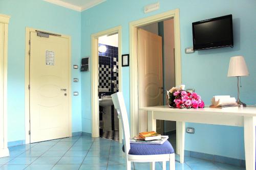 a room with blue walls and a table with a vase of flowers at Parco Dei Principi in Paestum