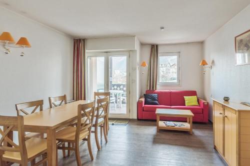 un salon avec une table et un canapé rouge dans l'établissement maeva Home Résidence la Rivière, à Chamonix-Mont-Blanc
