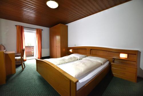 a bedroom with a bed with a wooden headboard and a window at Hotel&Wirtshaus Sonne in Weyregg