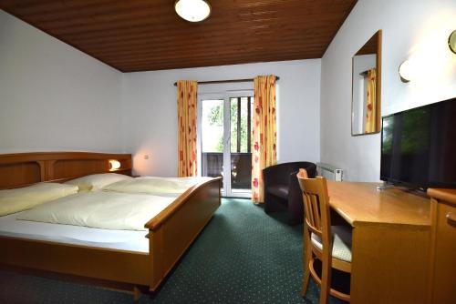 um quarto com uma cama, uma secretária e uma televisão em Hotel&Wirtshaus Sonne em Weyregg