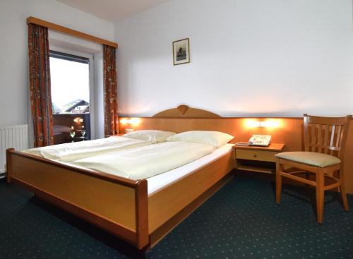 a bedroom with a large bed and a chair at Hotel&Wirtshaus Sonne in Weyregg