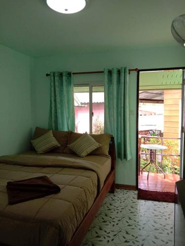 a bedroom with a bed with blue curtains and a window at Labelle House in Ko Lanta