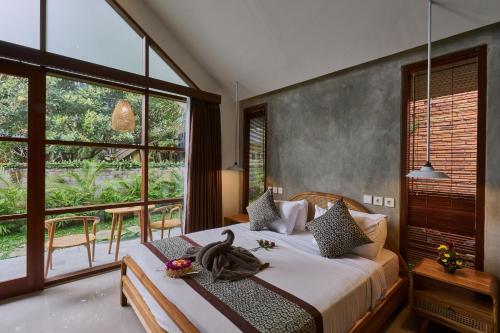 a bedroom with a bed and a large window at Yarama Cottages in Ubud