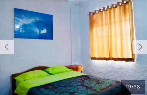 - une chambre avec un lit doté de draps verts et une fenêtre dans l'établissement Surf hostel My Friends, à Huanchaco