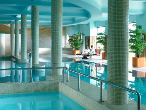a swimming pool in a hotel with people sitting on chairs at Kinsale Hotel & Spa in Kinsale