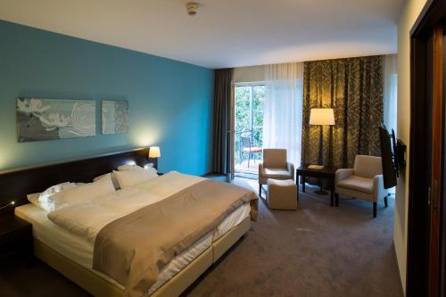 ein Schlafzimmer mit einem großen Bett in einem blauen Zimmer in der Unterkunft Heide Spa Hotel & Resort in Bad Düben