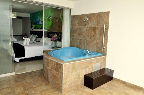 a bathroom with a blue tub and a bedroom at Mochican Palace Hotel in Huanchaco