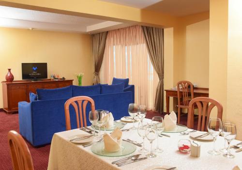 a dining room with a table and a blue couch at Hotel des Mille Collines in Kigali