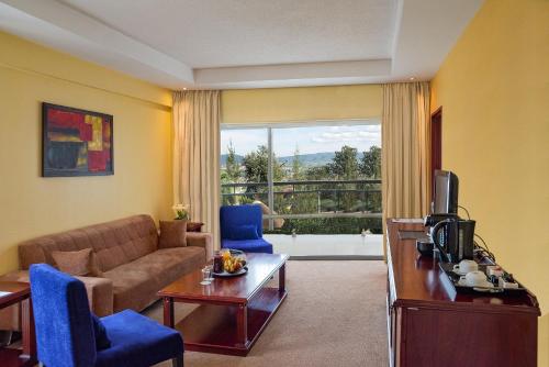 a living room with a couch and a tv at Hotel des Mille Collines in Kigali