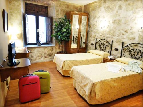 una habitación de hotel con 2 camas y 2 maletas en Palacio Antigua Audiencia en Ciudad-Rodrigo
