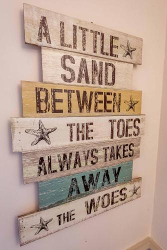a sign that says a little sand between at Aarondale Guest House in Hartlepool