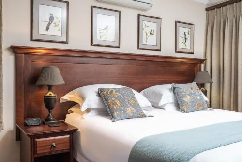 een slaapkamer met een groot bed met een houten hoofdeinde bij Blaauwheim Guest House in Somerset West