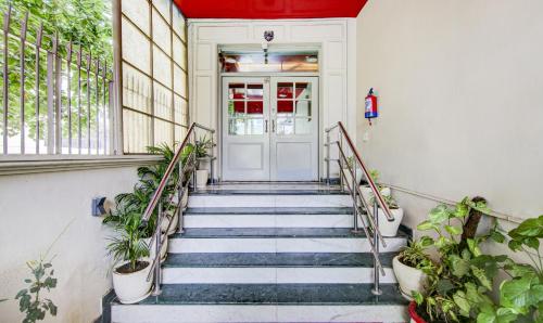a staircase leading to a white door with plants at Treebo Mall View, DLF Phase II in Gurgaon