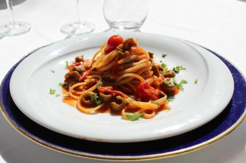 a plate of pasta on a table with wine glasses at Parco Dei Principi in Paestum