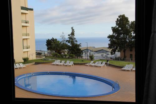 a view of a swimming pool from a window at CRISTO REI APARTMENT in Caniço