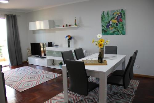 a dining room with a white table and black chairs at CRISTO REI APARTMENT in Caniço