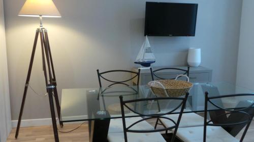 a room with a glass table with chairs and a television at 20 rue Gasté, proche gare SNCF de BREST in Brest
