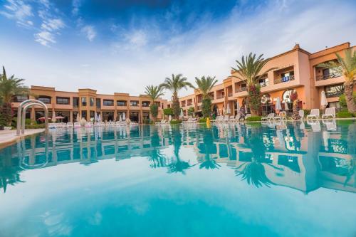 a pool at a resort with palm trees and buildings at Zalagh Kasbah Hotel & Spa in Marrakesh