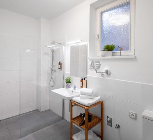 y baño blanco con lavabo y ducha. en City Leaf Apartments by Adrez en Praga
