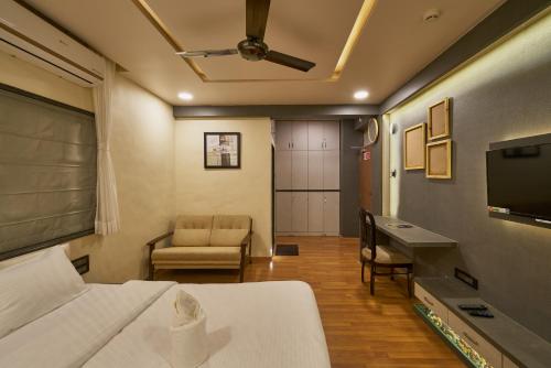 Habitación con cama, escritorio y TV. en Tranquil La Casa, en Pune