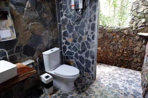 a bathroom with a toilet and a stone wall at Khao Sok Nature Resort in Khao Sok