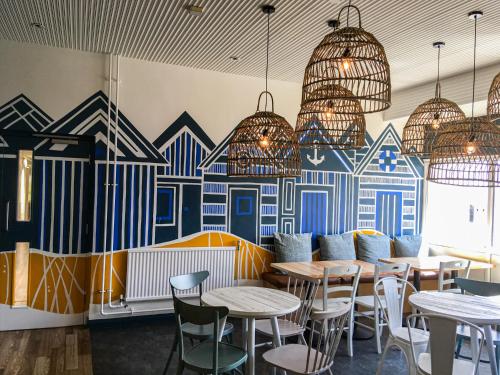 un restaurant avec des tables et des chaises et une fresque murale. dans l'établissement YHA Broad Haven, à Broad Haven