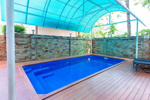 a swimming pool with an umbrella on a wooden deck at Naiyang Place - Phuket Airport in Nai Yang Beach
