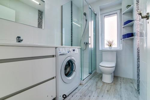 a bathroom with a washing machine and a toilet at Ravel in Alicante
