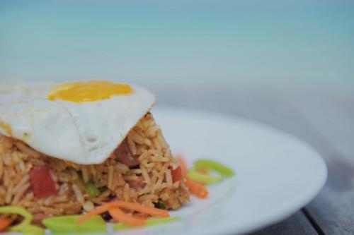 a plate of food with an egg on top of rice at Club Kaafu Maldives in Dhiffushi