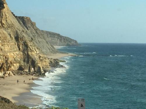 a beach with people on the sand and the ocean at Magoito1 in Sintra