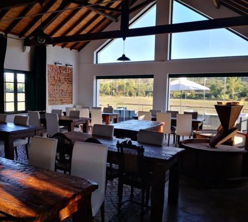 a dining room with tables and chairs and windows at Quinta da Varzea in Raposa
