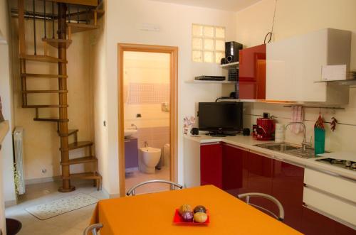 a kitchen with a orange table and a kitchen with a ladder at B&B La Perla nelle Dolomiti in Castelmezzano