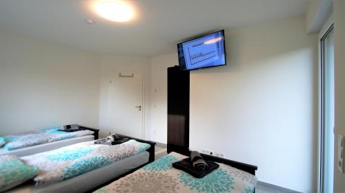 a room with two beds and a flat screen tv on the wall at Overath Luxus Apartments nähe Köln City/Messe in Overath