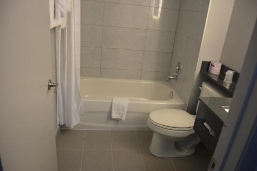 a bathroom with a toilet and a tub and a sink at Super 8 by Wyndham Windsor/Dougall in Windsor