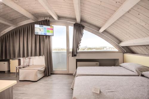 a bedroom with two beds and a tv on the wall at Hotel Gala in Misano Adriatico