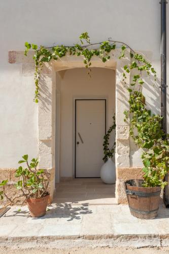 an entrance to a white building with potted plants at Masseria Monache in San Pietro Vernotico