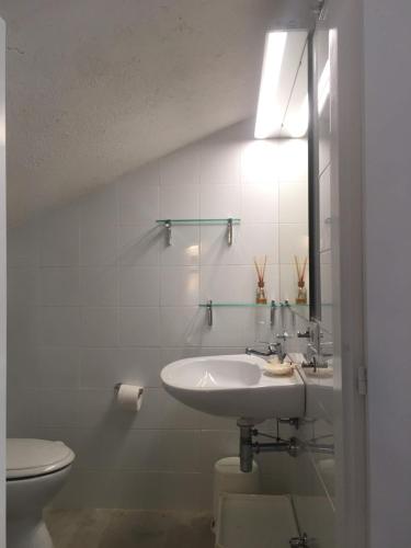 a white bathroom with a sink and a toilet at Casa Maia with shared swimming pool in Palau