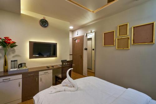 1 dormitorio con 1 cama, escritorio y TV en Tranquil La Casa, en Pune