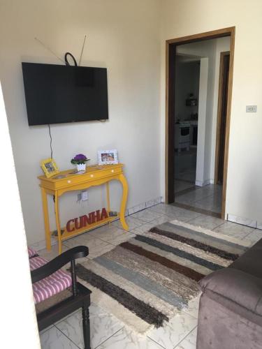 a living room with a table and a television on a wall at Hospedagem Aconchego in Cunha