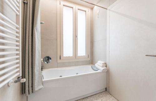 a white bathroom with a tub and a window at Rialto Luxury Flat in Venice