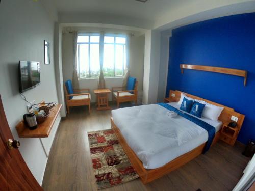 sypialnia z dużym łóżkiem z niebieską ścianą w obiekcie Aisha Guest House Bed & Breakfast w mieście Czerapuńdżi