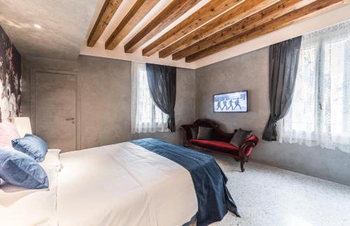 a bedroom with a white bed and a red chair at Rialto Luxury Flat in Venice