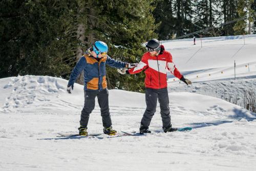 two people are standing in the snow on skis at Herbst Wohnerlebnis in Lofer