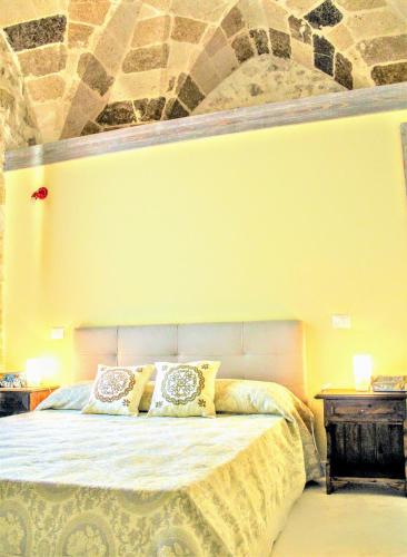 a bedroom with a bed with a stone wall at Dimora Vico dei Nohi in Lecce