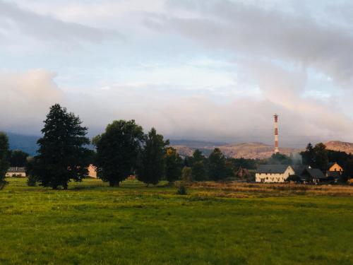 a field with a tower in the distance with a house at Sarnia Polana in Kostrzyca